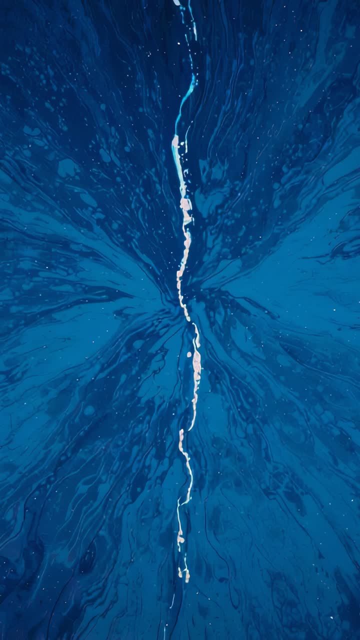 Video verticale: striscia bianca fluida che scivola verso il basso per gravità su un pannello blu da studio formando goccioline