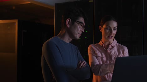 Diverse-female-and-male-it-technicians-using-laptop-checking-computer-server