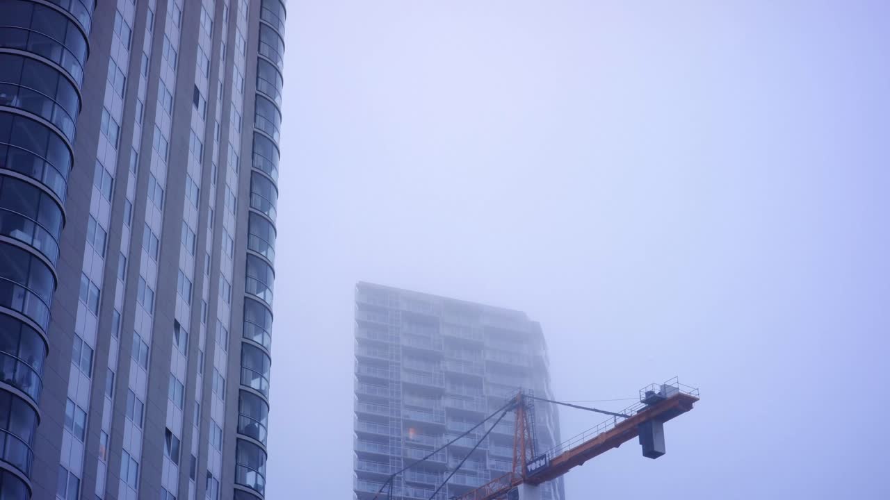 Fog passing by crane amidst architecture in the Rotterdam region.