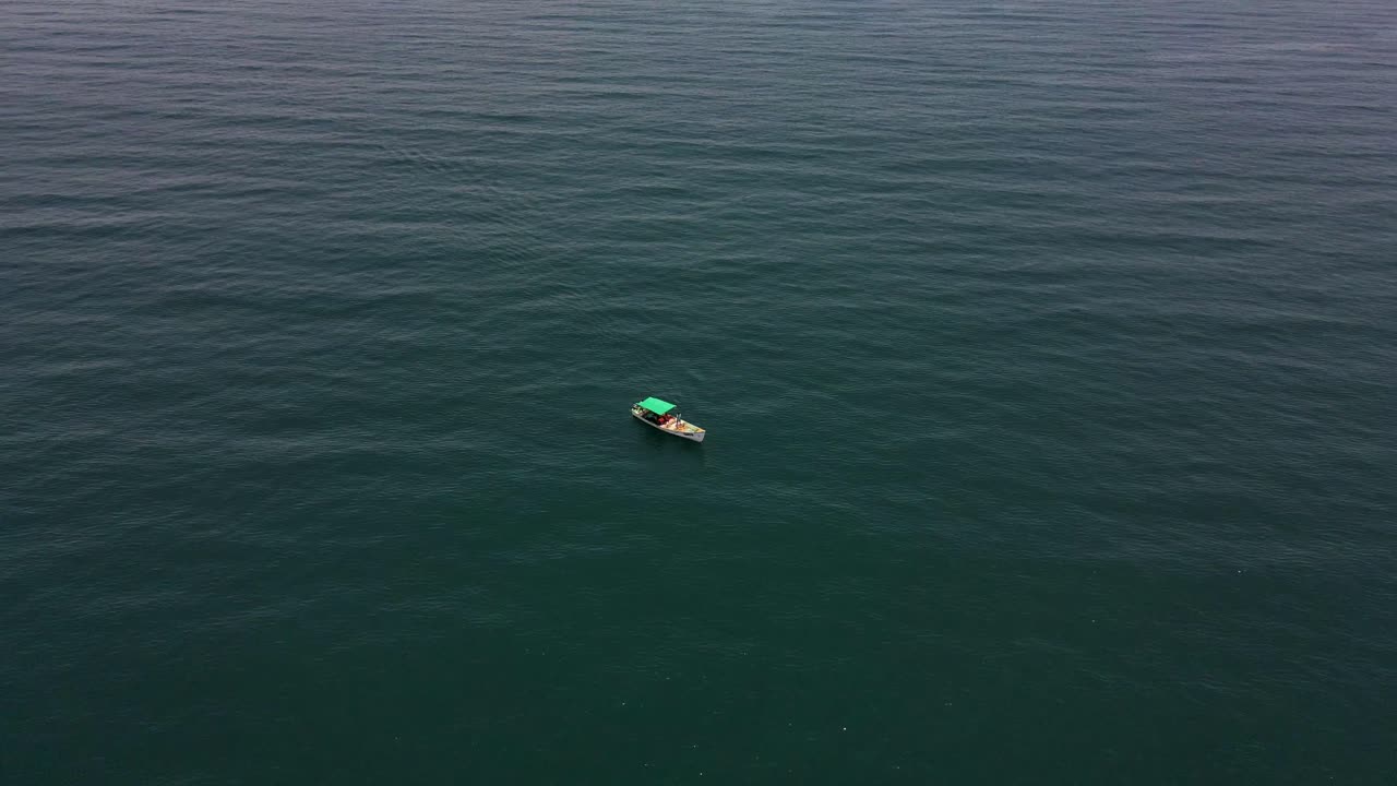 Aerial drone shot of a fisher boat surrounded by the calm and infinite beauty of the ocean.