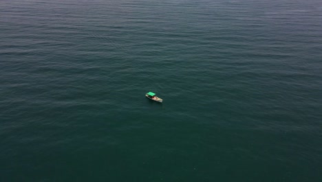 aerial drone shot of a fisher boat surrounded by the calm and infinite beauty of the ocean.