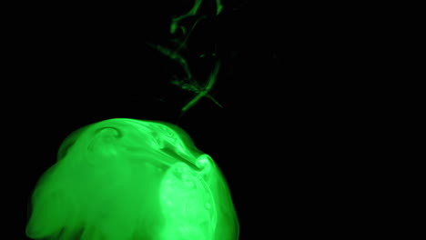 movimiento lento de humo verde que se eleva iluminado en una habitación oscura