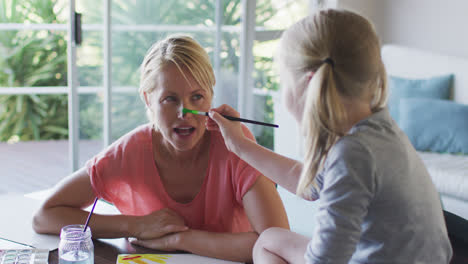 Side-view-of-Caucasian-woman-painting-with-her-daughter-at-home