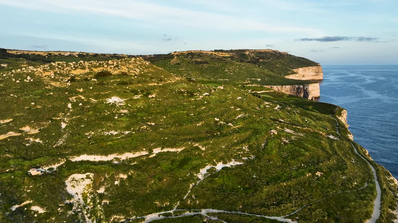 Stunning drone view of Migra l-Ferha’s winding countryside trails atop dramatic limestone cliffs. Highlights the unique blend of lush terrain and rugged coastline along Malta’s wild western edge.