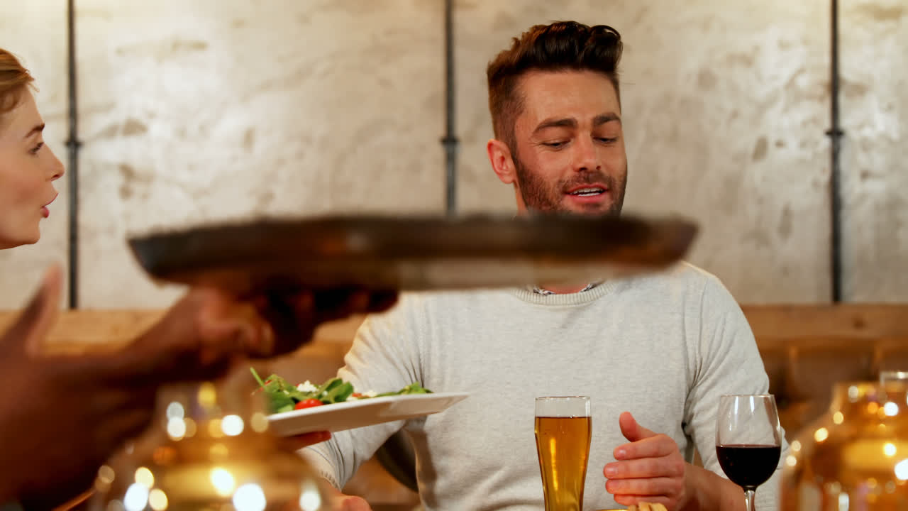 amigos felices ofreciéndose comida unos a otros en la mesa de la cena 4k 4k
