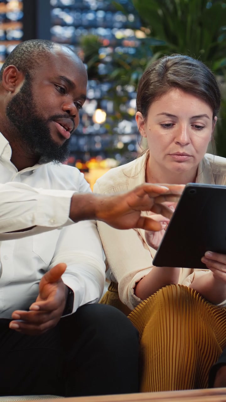 Vertical video Businessman points to tablet screen during rooftop lounge workspace presentation