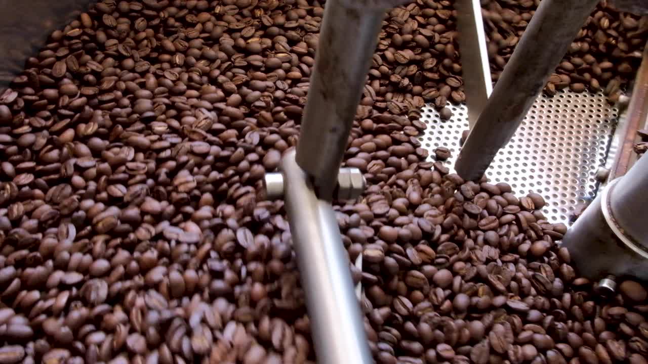 Closeup of golden brown roasted coffee beans being cooked in a commercial coffee roasting machine at local cafe