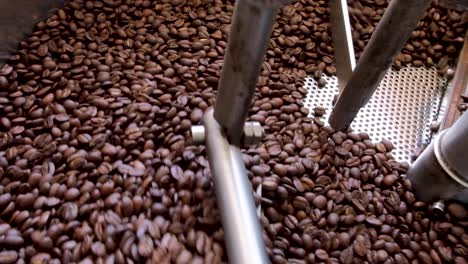 primer plano de granos de café tostados dorados que se cocinan en una máquina tostadora de café comercial en el café local