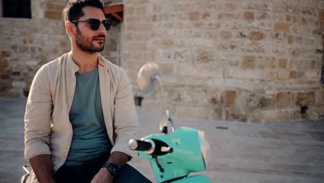 young man sitting on scooter and relaxing in old city