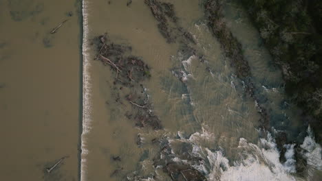 Top-down-shot-of-a-fast-flowing-waterfall-with-dead-trees-floating-in-Lake-Sequoyah