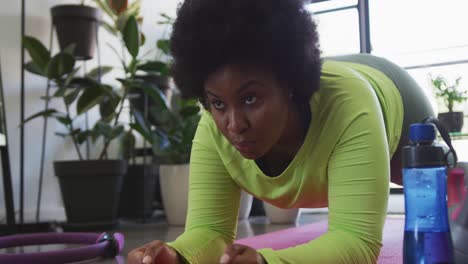 mujer afroamericana de tamaño grande acostada en un tapete de ejercicio haciendo ejercicio