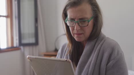 woman in glasses using digital tablet at home