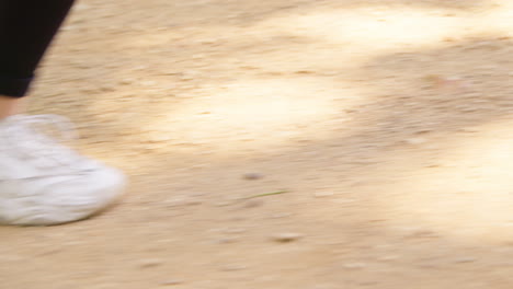 close up side view of woman wearing training shoes exercising running along path in city park