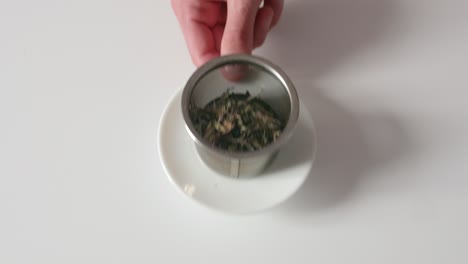 Bulk-tea-leaves-in-a-metal-tea-filter-being-picked-up