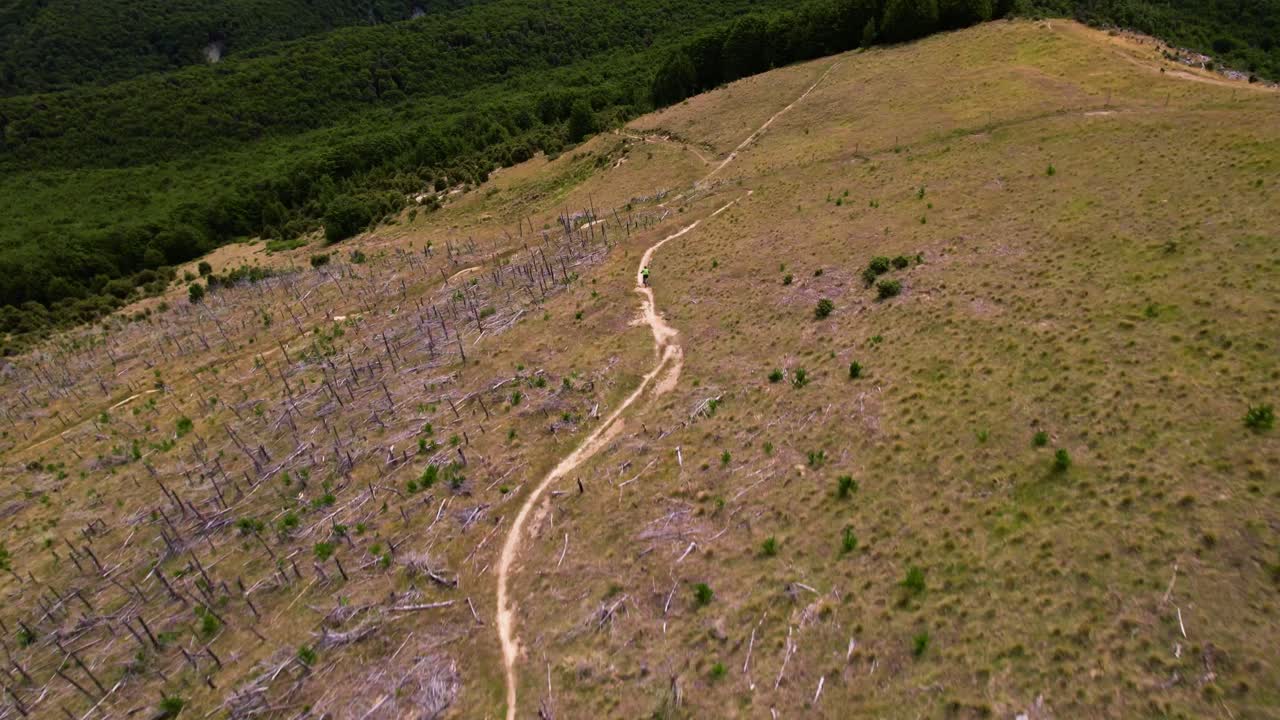 Aerial view following a mountain bike, riding down a hill in Cragieburn, NZ