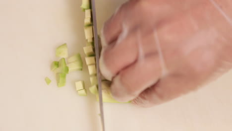 chef cutting ripe avocado into small pieces for sushi rolls