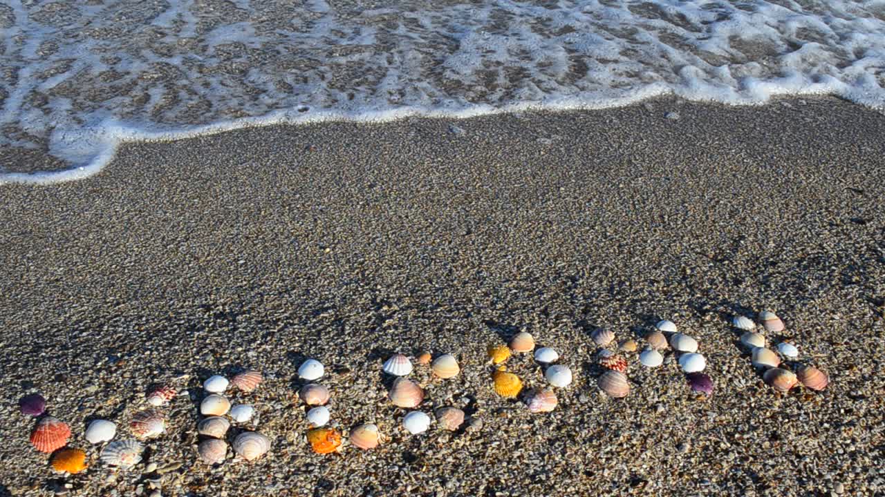 Iscrizione di benvenuto sulla sabbia, la spiaggia. Servizio fotografico sulla spiaggia