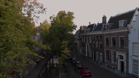 Aufwärtsneigung-Aus-Der-Luft-Vom-Kanal-Am-Frühen-Morgen-Blick-Auf-Die-Nieuwe-Gracht-In-Der-Mittelalterlichen-Niederländischen-Stadt-Utrecht-Bei-Sonnenaufgang,-Der-Zwischen-Den-Herbstbäumen-Aufgeht-Und-Das-Breitere-Stadtbild-Enthüllt