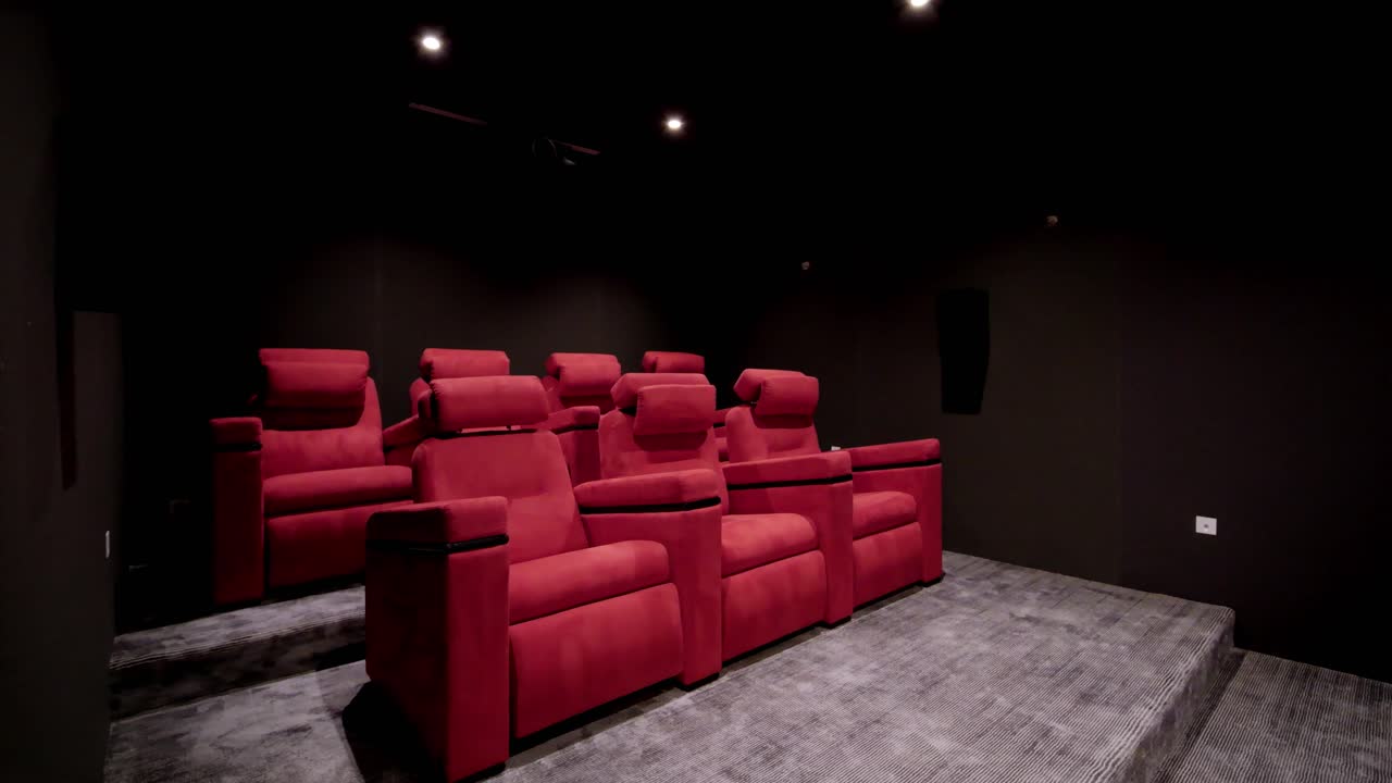 foto reveladora de una sala de cine en casa con sillas de color rojo brillante