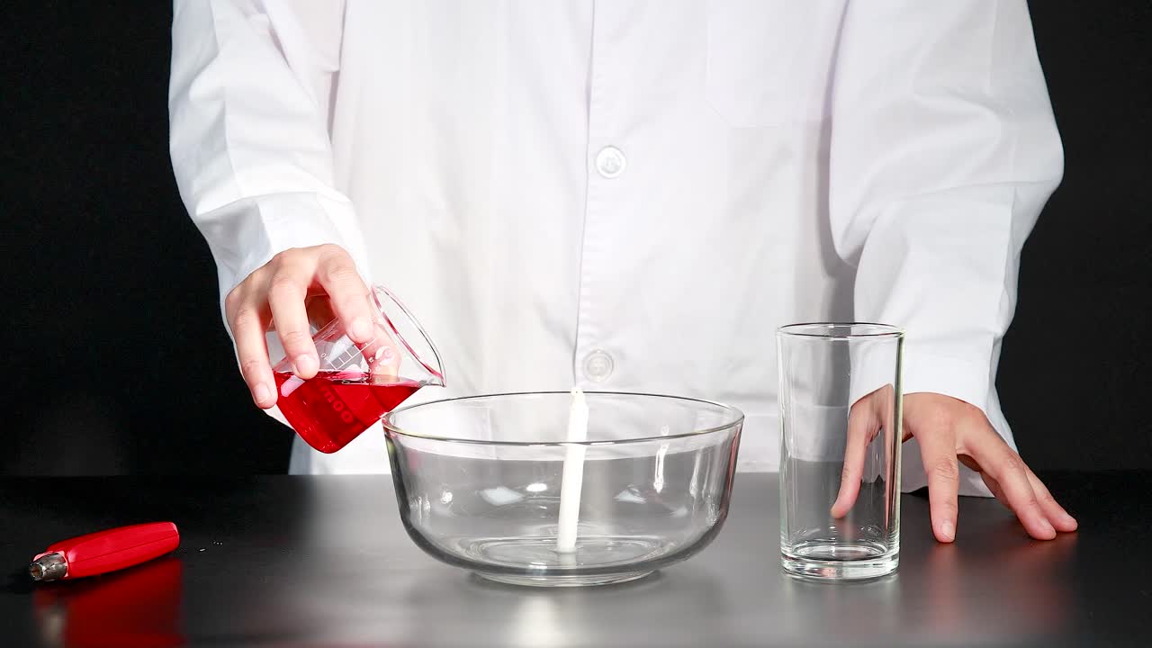un científico demuestra una reacción química usando una vela para crear una diferencia de presión, haciendo que el agua se eleve en un vaso