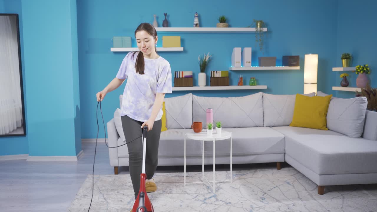 집을 청소하는 젊은 여성이 소파에 앉아 휴식을 취합니다.