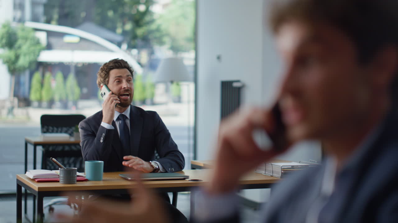 Dipendente aziendale che parla al telefono in un ritratto di coworking. Colleghi che comunicano