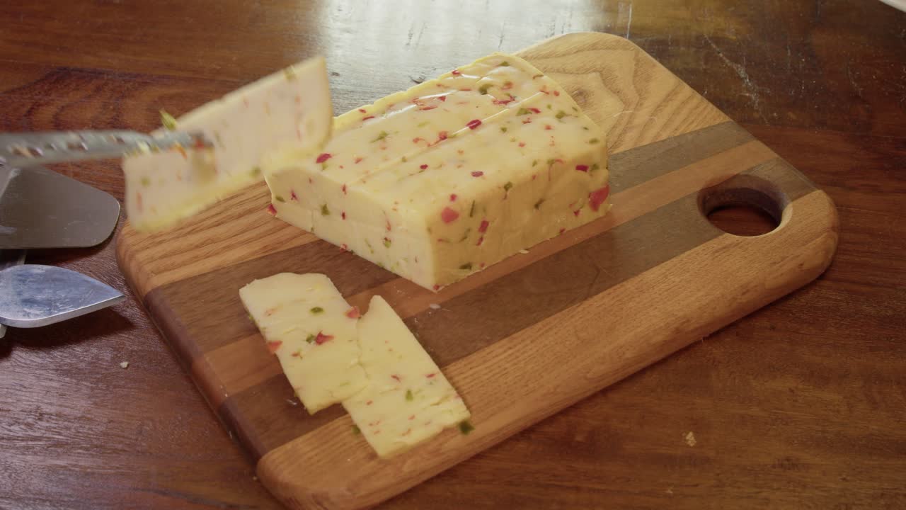 cuchillo de queso utilizado para cortar una rebanada de queso de pimienta roja picante en el bloque