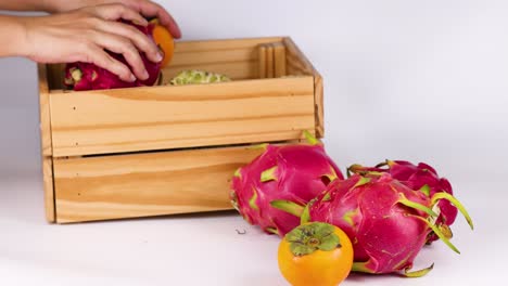 manos colocando frutas en una caja de madera