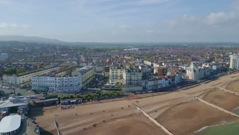 Flying-around-Eastbourne-sea-front,-pier,-buildings,-road-and-cars