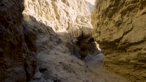 a zoom in drone shot from inside of a desert slot canyon at sunset