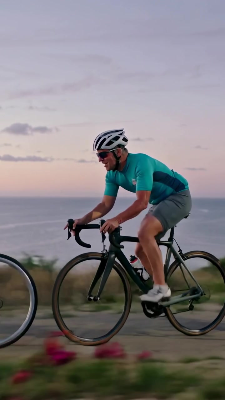 Video verticale: Ciclista che pedala, inizia un giro su un sentiero costiero con una bici da corsa, indossando una maglia color verde acqua.