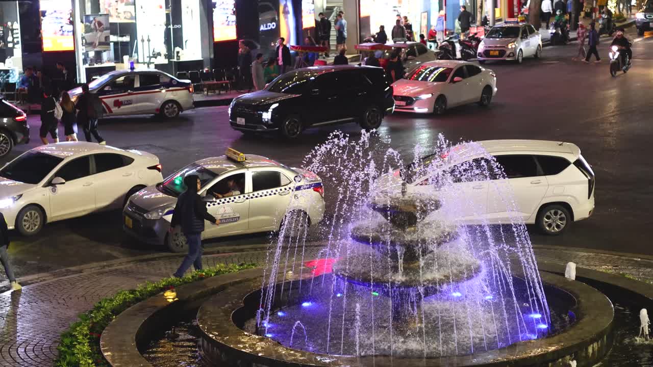 다채로운 불빛과 바쁜 교통이 있는 분수