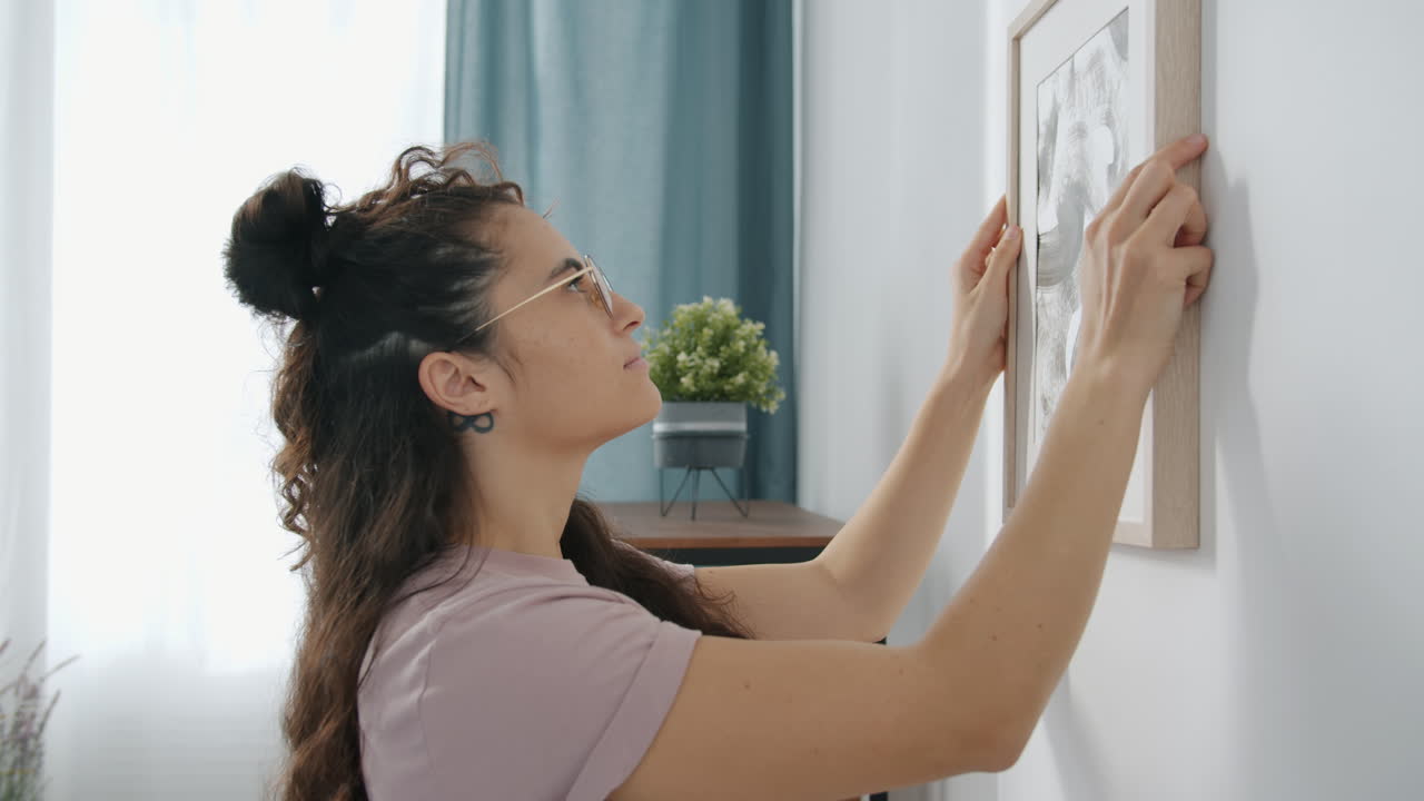 Woman Hanging a Picture on Wall