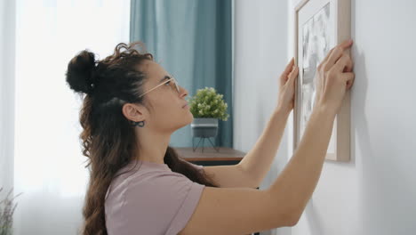 woman hanging a picture on wall