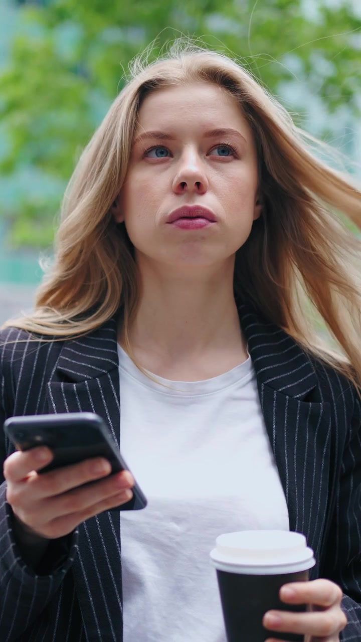 Giovane imprenditrice che usa lo smartphone e beve caffè all'aperto