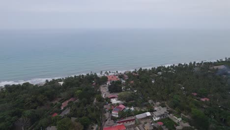 Drone-Asciende-Sobre-La-Selva-Tropical-Boscosa-Y-La-Costa-Oceánica-En-Palomino-Colombia