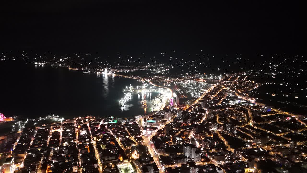 Cinematic nighttime drone footage of Batumi skyline and illuminated skyscrapers.
