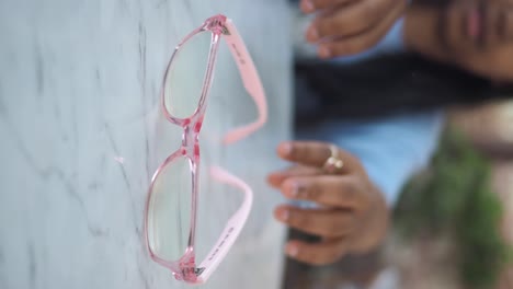 woman holding pink eyeglasses on a marble table