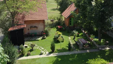 hermoso hogar de pueblo pequeño con 2 casas y baño al aire libre en el jardín con césped verde con flores y camino de piedra rodeado de árboles