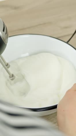 vertical shot of mixing egg whites with an electric mixer as part of tiramisu preparation
