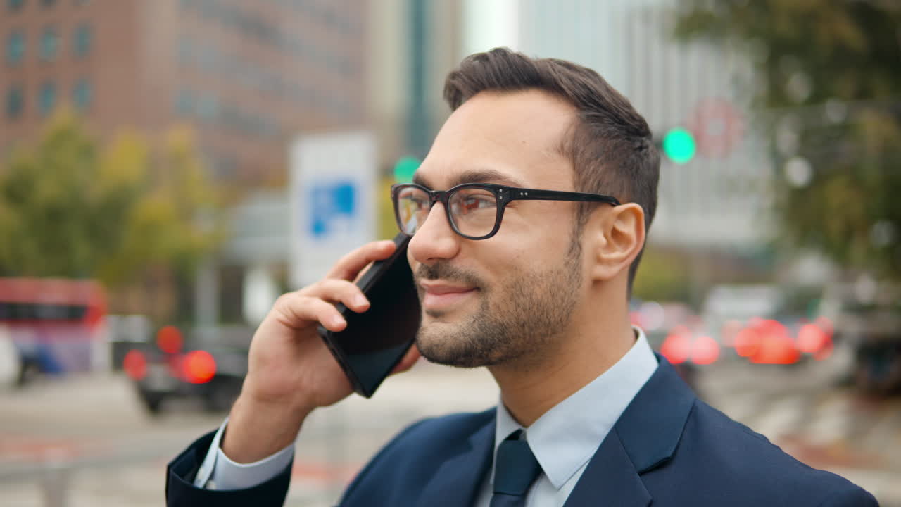 retrato de un feliz hombre de negocios hablando en el teléfono móvil de pie en una concurrida calle de la ciudad con el tráfico borroso en el fondo