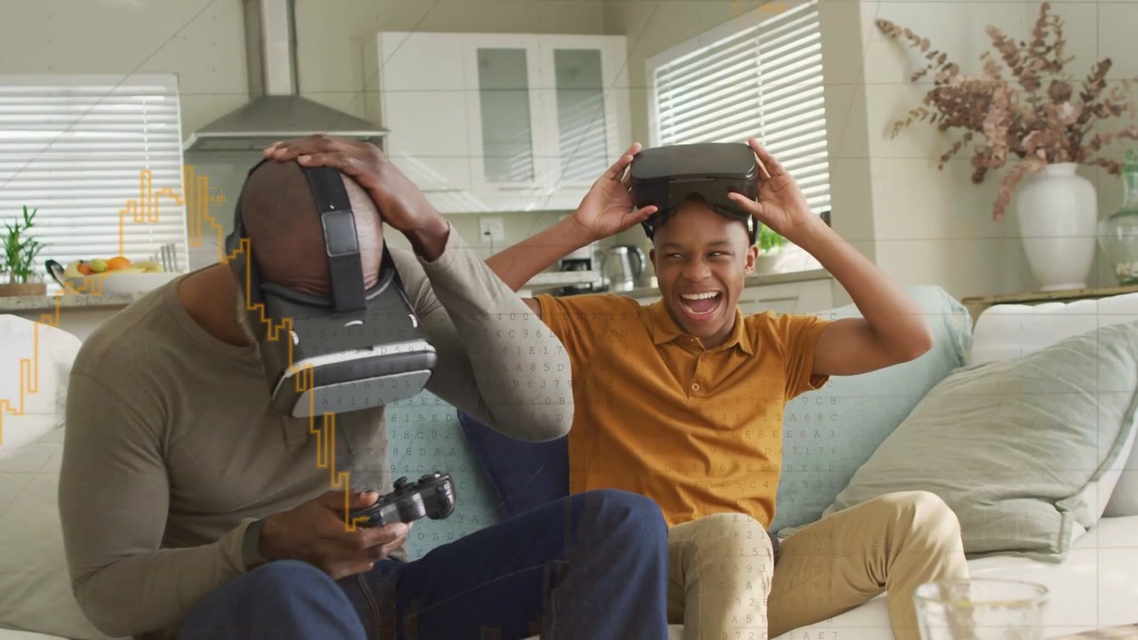 Padre e figlio che giocano a videogiochi VR, il padre che attiva il controller, il figlio che esulta e poi si toglie le cuffie.