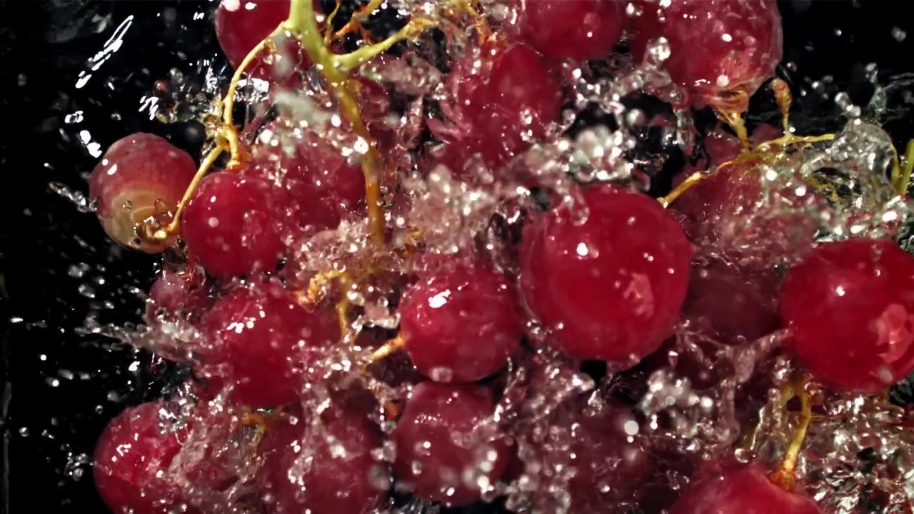 Uva rossa fresca con schizzi d'acqua su sfondo nero
