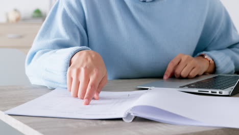 hands, reading notes and typing on laptop