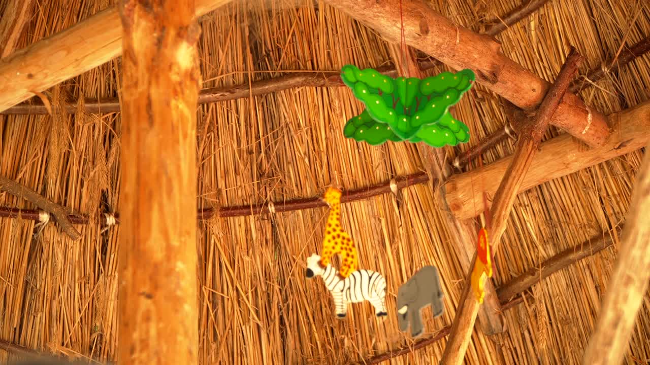 Rattle above the crib is spinning. animals hang on it. against the ceiling of wood and reeds. There's no one , the toy is spinning