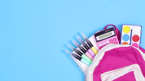 school backpack with school stationery move and paper for text appear on blue background. stop motion