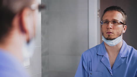 tired doctor takes off surgical mask and touches hair