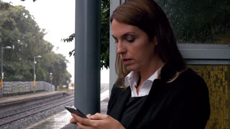 Businesswoman-waiting-for-a-train-on-the-phone