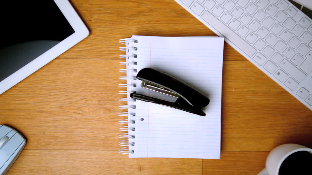 Stapler landing on notepad on office desk