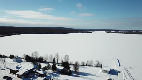 Cold-sunny-blue-sky-winter-day-at-a-frozen-lake-in-the-northern-countryside-of-Canada---Drone-4k-Aerial